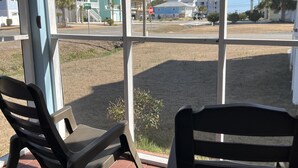 Un portico con due poltrone a dondolo, vista su una strada con case e un segnale di stop.