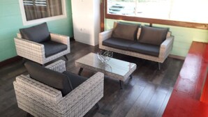 Une pièce meublée avec des meubles en osier, comprenant deux fauteuils et un canapé, disposés autour d’une table basse centrale.