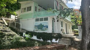 Une maison à deux étages, à la façade verte et blanche, dotée d’un balcon et ornée d’une fresque représentant une tortue sur le côté.