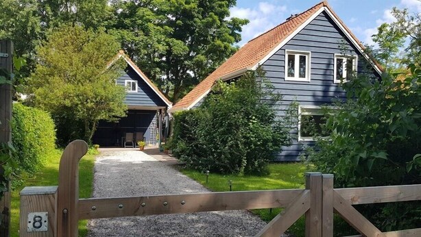 A residential property with a gravel driveway leading to a wooden gate marked with the number 8.