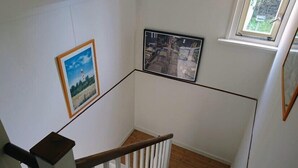 A staircase with a wooden handrail and white balusters, leading to a landing with two framed pictures on the walls.