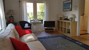 A living room with a sofa, a television, a small table, and a bookshelf.