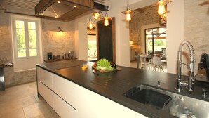 A modern kitchen with a large island, stainless steel appliances, and pendant lighting.