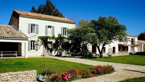 A white building with a tiled roof, a stone wall, and a gravel pathway.