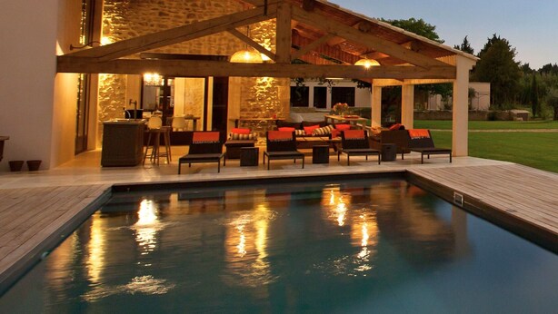 A modern house with a swimming pool, outdoor seating, and a stone facade.