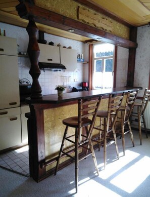 Una cocina con taburetes de madera, un ventanal con vistas y techo de madera.