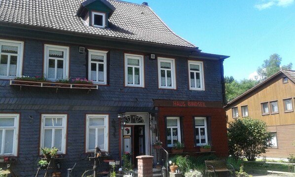 A two-story building with a dark blue facade, multiple windows with white frames, and a sign reading 'HAUS BINDSEIL'.