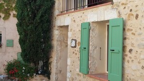 A stone building with a balcony, green shutters, and potted plants. - Village house with lake view (Sainte-Croix-Du-Verdon)