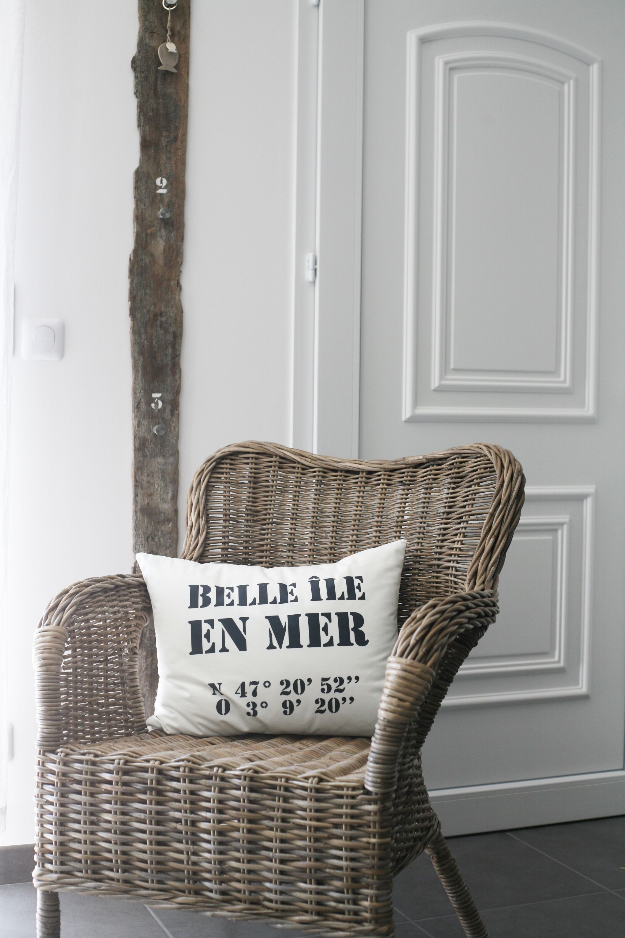A wicker chair with a pillow that has coordinates written on it.
