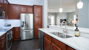 A modern kitchen with stainless steel appliances, wooden cabinets, and a marble countertop.