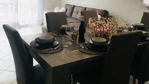 Ein Essbereich mit einem für vier Personen gedeckten Tisch, einer Couch im Hintergrund und einem Gemälde an der Wand.