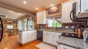 A spacious kitchen with white cabinets, granite countertops, and a dishwasher. - Spacious Lake Home w/ Dock, Hot Tub & Views (McHenry)