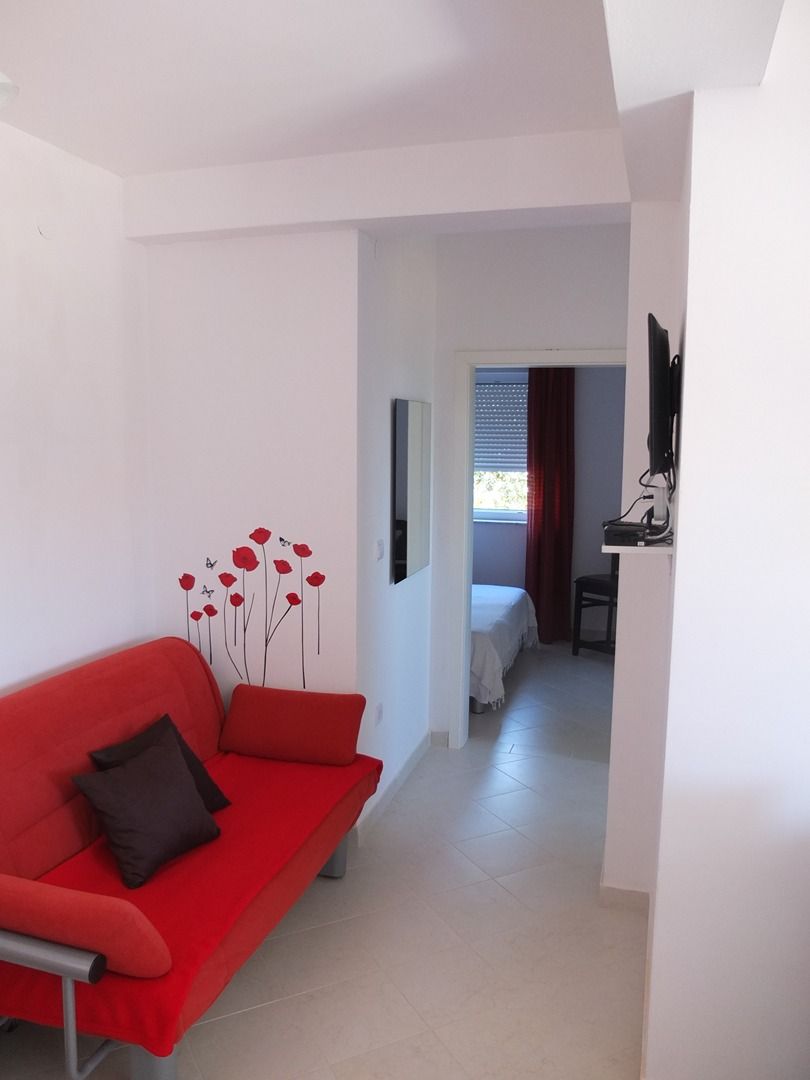 A modern living room with a red sofa, a small table, and a decorative wall with red flowers.