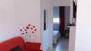 A modern living room with a red sofa, a small table, and a decorative wall with red flowers.