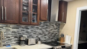 Una cocina moderna con electrodomésticos de acero inoxidable, armarios de madera y salpicadero de azulejos.