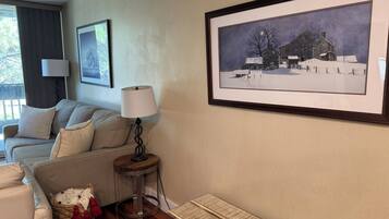 A cozy living room with a sofa, a lamp, a framed picture, and a small table.