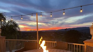 A deck with a fire pit, string lights, and a view of the sunset over a cityscape. - 10,000 ft² view estate with 7 Bdm Suites, Resort Pool, Theatre, Gym, Game Room! (Fallbrook)