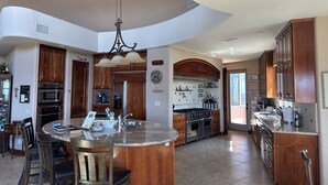 A spacious kitchen with a central island, wooden cabinets, and a large chandelier. - 10,000 ft² view estate with 7 Bdm Suites, Resort Pool, Theatre, Gym, Game Room! (Fallbrook)