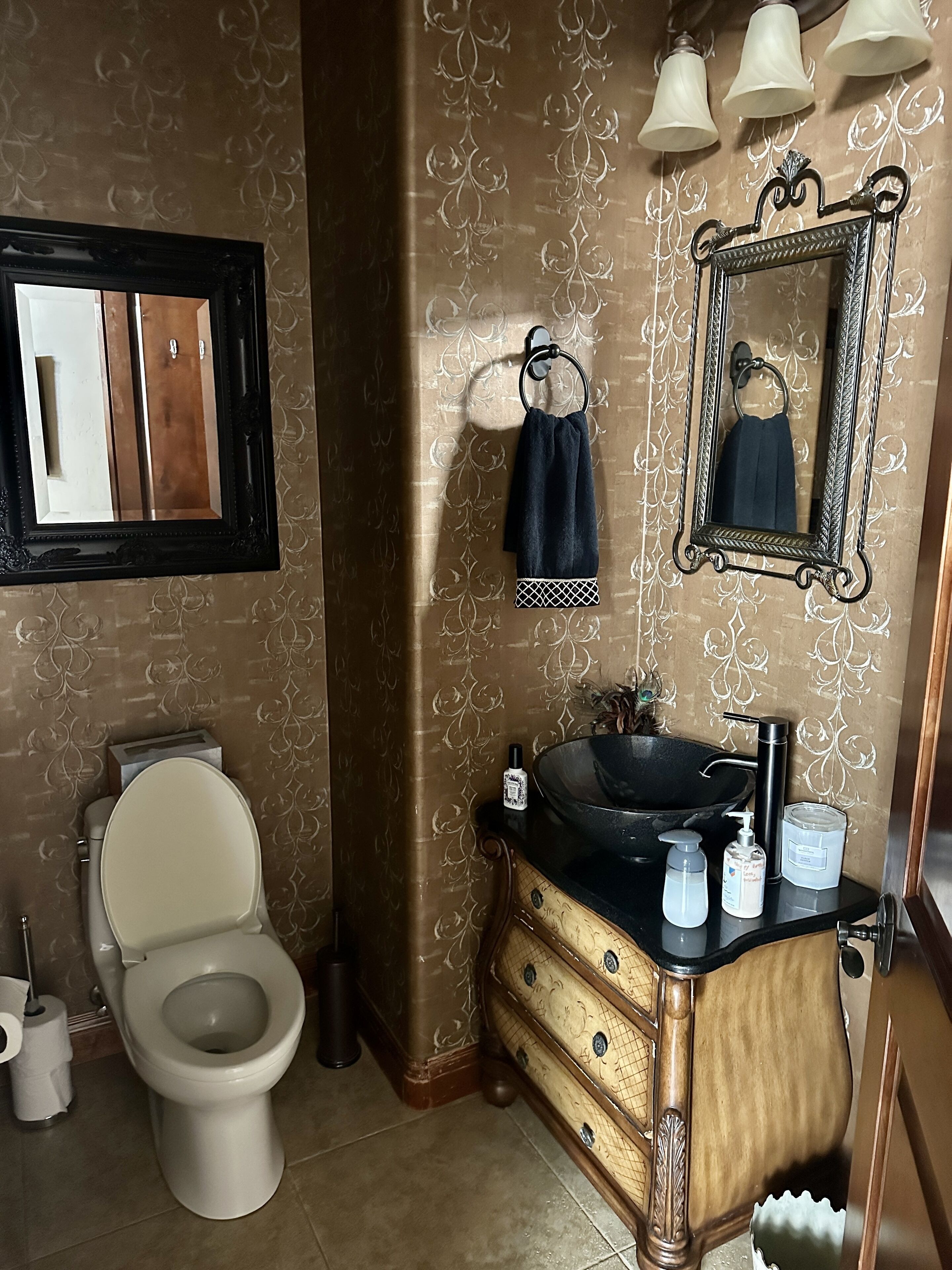 A bathroom with a toilet, vanity with a sink, and a mirror.