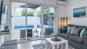 A modern living room with a grey sofa, a white coffee table, and a view of a pool through large glass doors. - Gorgeous home in Vrsi Mulo with sauna (Vrsi Mulo)