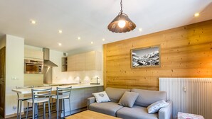 Una cocina moderna con paredes de madera, un comedor con sillas, un sofá y un aparador de madera.