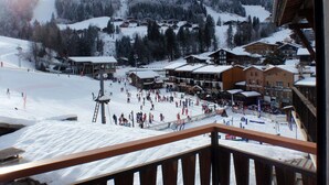 Un centro de esquí nevado con varios edificios, un telesilla y una multitud de personas en las pistas.