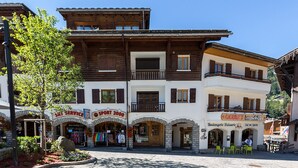 Un edificio alpino tradicional con varias tiendas en la planta baja, incluyendo un servicio de esquí y una tienda de deportes.