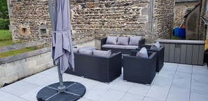 A patio with wicker furniture and an umbrella, set against a stone wall.