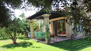 A covered patio area with a green lawn, a table with chairs, and a hanging plant. - VILLA "LOUISA" 4P-PRIVATE POOL GROUND FLOOR PARKING COMPLEX DYARSHEMSI  (Oulad Teima)