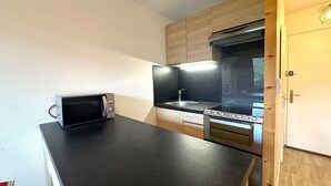 A compact kitchen with a microwave, stove, and sink.