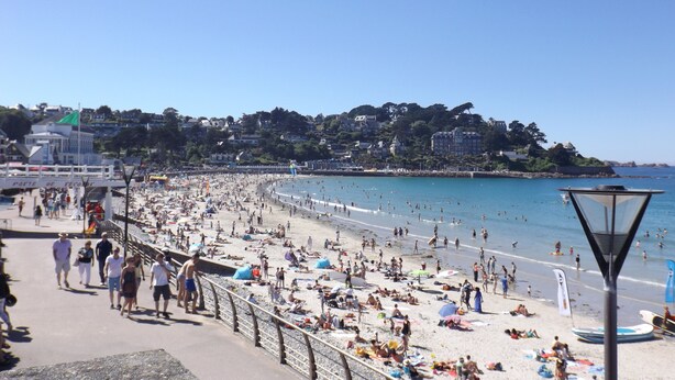 A crowded beach with people sunbathing and swimming, a promenade with a railing, and buildings in the background. - Plage de Trestraou, Apartment facing the sea, 40 m² for 4 people, Wi Fi (Perros-Guirec)