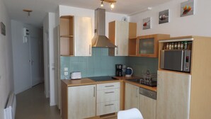 A compact kitchen with wooden cabinets, a microwave, a coffee maker, and a toaster. - Plage de Trestraou, Apartment facing the sea, 40 m² for 4 people, Wi Fi (Perros-Guirec)