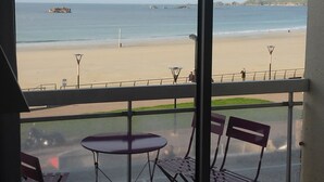 A balcony with a view of a beach, a table, and two chairs. - Plage de Trestraou, Apartment facing the sea, 40 m² for 4 people, Wi Fi (Perros-Guirec)