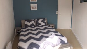 A bedroom with a bed, two nightstands, a door, and two framed pictures on the wall. - Plage de Trestraou, Apartment facing the sea, 40 m² for 4 people, Wi Fi (Perros-Guirec)