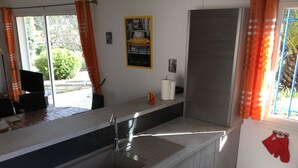 Une cuisine moderne avec un évier encastré, une fenêtre ornée de rideaux orange et une affiche accrochée au mur.