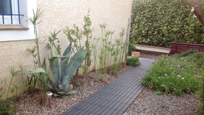 Un sentier de jardin bordé de différentes plantes et agrémenté d’un banc.