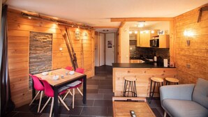 A cozy wooden interior with a dining area, a kitchen, and a living space.