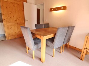 Un coin repas avec une table en bois et des chaises à revêtement gris, un meuble en bois et un luminaire fixé au mur.