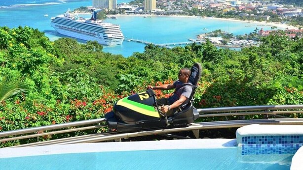 Una persona en un telesilla con vistas a un crucero, una playa y una zona turística.