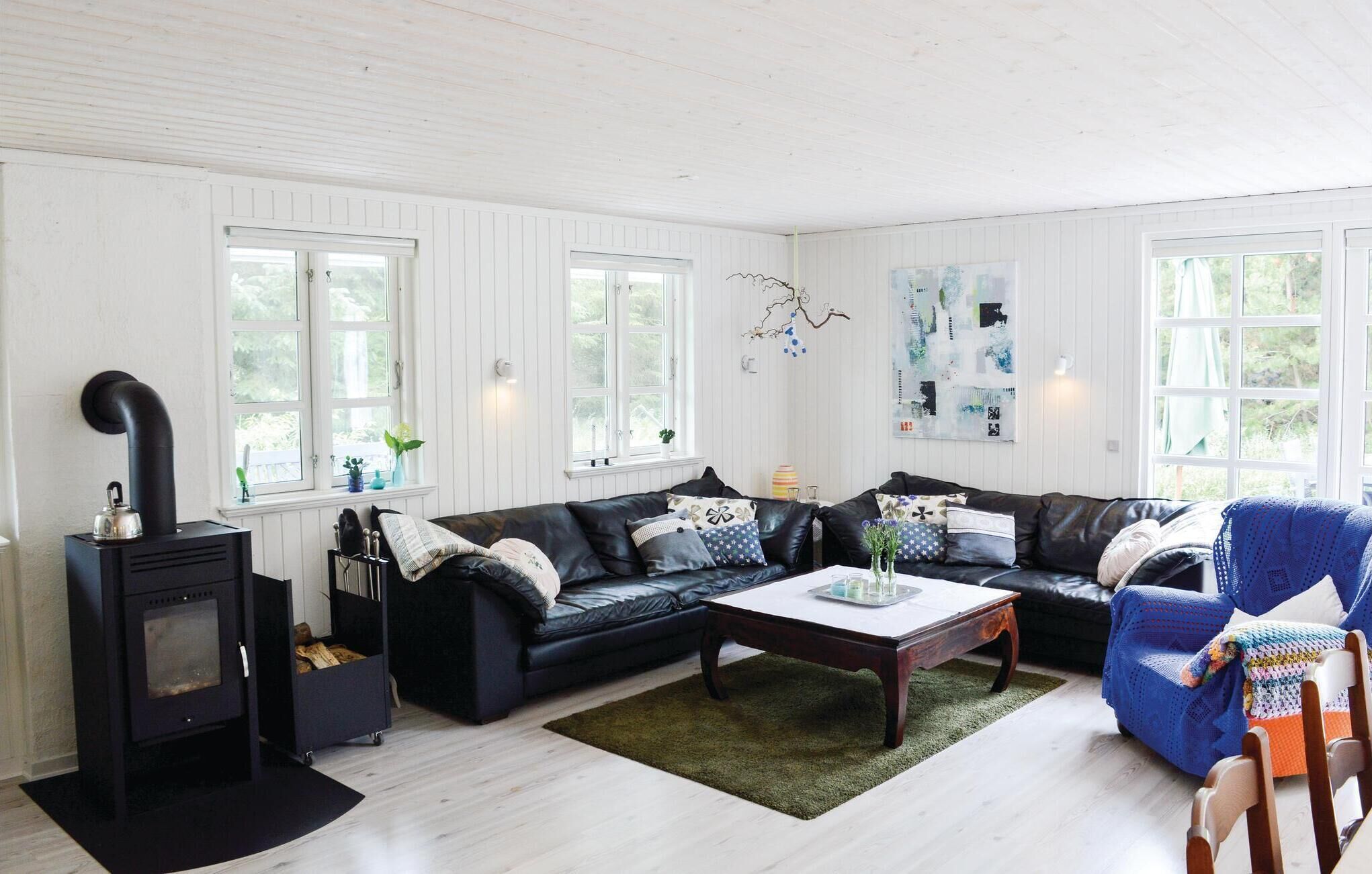 A cozy living room with a black leather sofa, a wooden coffee table, and a black fireplace.