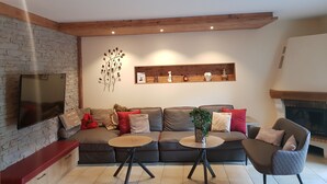 Ein modernes Wohnzimmer mit einer Couch, zwei Beistelltischen, einem Kamin und einem Wandbild.