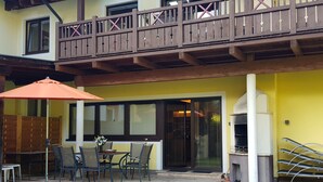 Eine Terrasse mit Gartenmöbeln, einem Grill und einem hölzernen Balkon.