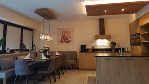 Eine moderne Küche mit Holzschränken, einem Essbereich mit Tisch und Stühlen sowie einer Pendelleuchte.