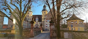 A historic building with a central tower, stone walls, and a cobblestone pathway leading to the entrance.
