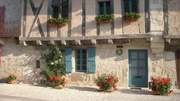 A traditional stone building with multiple windows, some with shutters, and flower boxes on the upper windows. - In a listed village, half-timbered house overlooking a wooded valley (Montjoi)