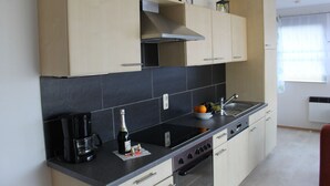 Een moderne keuken met lichte houten kastjes, een zwart aanrecht en een ingebouwde oven.