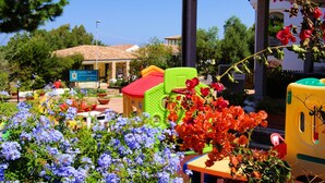 Een hotel met kleurrijk tuinmeubilair en een bord waarop een restaurant wordt aangegeven.