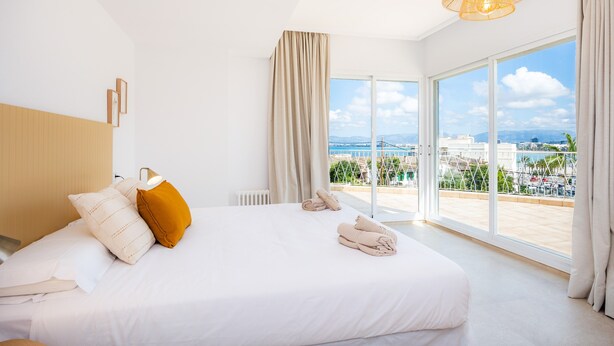 Une chambre d’hôtel moderne avec un grand lit, une vue sur la ville et un balcon.