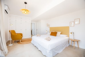 Un dormitorio con cama, una silla, una mesita de noche y una lámpara.