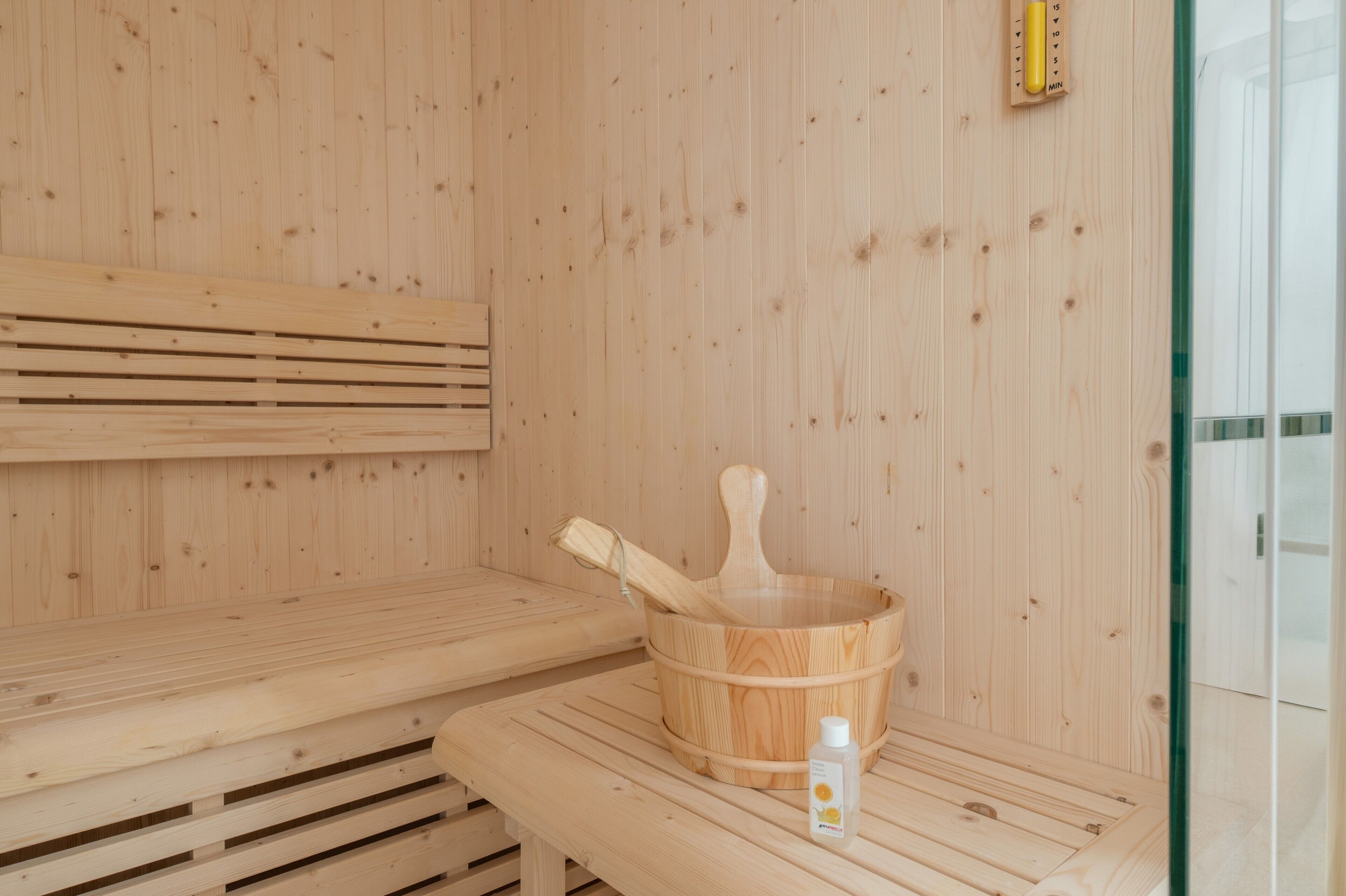 Una sauna de madera con un banco y un balde de madera.